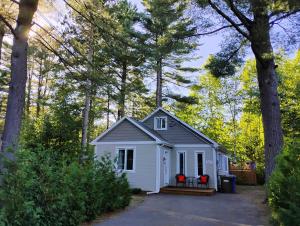 a small white house in the woods at Serene Getaway Nordic Spa , Sauna, Nature & Pool in Rawdon