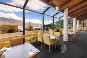 a restaurant with tables and chairs and a view of the mountains at Copthorne Hotel and Apartments Queenstown Lakeview in Queenstown +21 photos