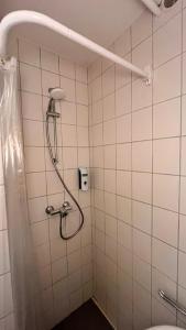 a shower in a bathroom with white tiles at Studio Ohlendorf 3 Min zur A7 in Seevetal