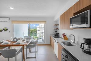 a kitchen with a table and chairs and a counter top at Upstay Brand New 3BR Viva Jaco Residences in Jacó +14 photos