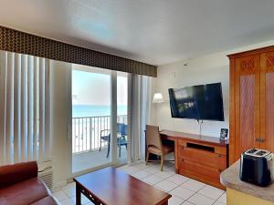 un salon avec une télévision et un bureau avec une table dans l'établissement Harbour Beach Resort 303, à Seabreeze