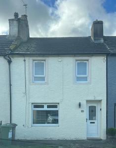 a white house with a dog sitting in a window at Cottage in Seaton in Siddick
