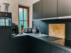 Una cocina con gabinetes negros y un fregadero. en Studio Wasserfall, en Flattach