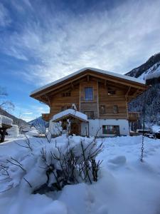 una cabaña de madera con nieve delante en Studio Wasserfall, en Flattach