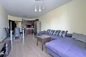 Una sala de estar con un sofá morado y una cocina. en Apartments Nessebar, en Nesebar