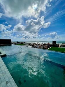 ein großer Swimmingpool mit dem Meer im Hintergrund in der Unterkunft Holanda's Prime in Tambaú