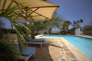 a swimming pool with two chairs and an umbrella at Munje Luxury Beach Villas in Msambweni