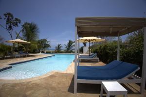 a swimming pool with two chairs and umbrellas at Munje Luxury Beach Villas in Msambweni