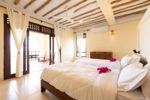 a bedroom with a large white bed with flowers on it at Munje Luxury Beach Villas in Msambweni +31 photos