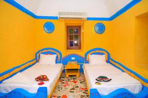 two beds in a room with yellow walls at Nubian Palace Eco Lodge in Aswan +92 photos