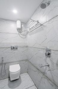 a white bathroom with a toilet and a shower at Hotel Saffron Groves in Hyderabad