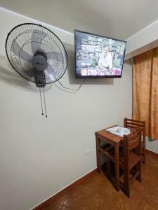 a room with a fan and a table and a tv at Hostal Leo in Lima