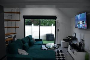 a living room with a green couch and a tv at Eden House in Saint-Pierre-Canivet