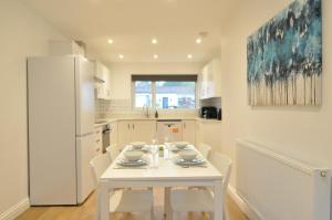 a white kitchen with a white table and a white refrigerator at The Swift-Bright, Modern 5-Bed Family Home Nr Bath in Rudloe