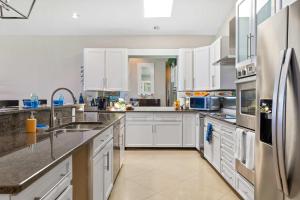 une cuisine avec des armoires blanches et des appareils en acier inoxydable dans l'établissement Laguna Del Mar #19 - Seven Mile Beach, à Dog City 33 autres photos