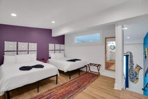 2 Betten in einem Zimmer mit lila Wänden in der Unterkunft Elegant Stay Across From Fq W Free Parking in New Orleans