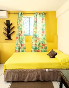 a bedroom with a bed with yellow walls and a window at Zinnia Apartments Antigua in Potters Village