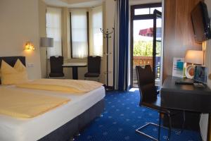 Una habitación de hotel con una cama, un escritorio y una mesa. en Hotel Kärntnerhof Velden, en Velden am Wörthersee