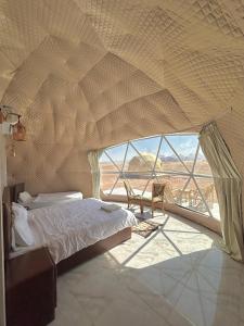 a bedroom with a bed and a large window at Wadi Rum March in Aqaba