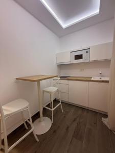 a kitchen with a table and two stools in it at Apartamento LORETO - Hotel Ruta del Segur in Pontones