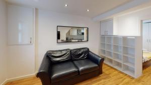 a black leather couch in a room with a mirror at Modern 1 Bed City Centre Flat in Nottingham