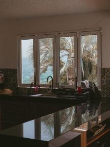 a kitchen with a sink and a window with a palm tree at Casa Cumbres - Ocean View in Puerto Escondido +52 photos
