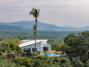 a house with a palm tree and a swimming pool at Casa Cumbres - Ocean View in Puerto Escondido