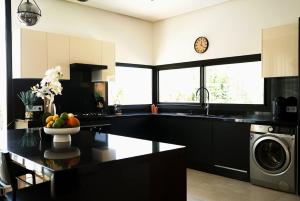 La cuisine est équipée de comptoirs noirs, d'un évier et d'un lave-vaisselle. dans l'établissement Villa Lily, à Tameslouht