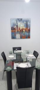 a glass table with chairs and a painting on the wall at Maison de cèdre in Azrou