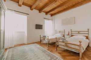 Dos camas en una habitación con paredes blancas y techos de madera. en Fascino in Centro with private parking and two Rooms, en Ascoli Piceno