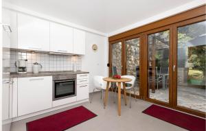 a kitchen with white cabinets and a table and a dining room at 1 Bedroom Nice Apartment In Mali Losinj in Cunski