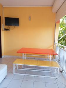 a table on a balcony with a tv on the wall at Villa Grandes pièces in Petit-Bourg