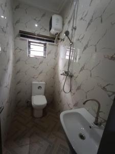 a bathroom with a white toilet and a sink at Ike Service Apartments in Owerri