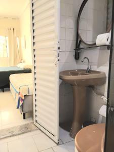 a bathroom with a sink and a mirror at Residencial Praia Bertioga Pé na Areia in Bertioga