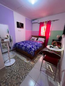 een slaapkamer met een bed, een tafel en een stoel bij Vision Hébergement in Bonabéri