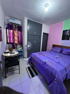 een slaapkamer met een paars bed en een tafel bij Vision Hébergement in Bonabéri
