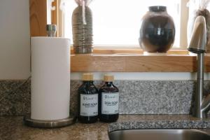 two bottles of vinegar sitting on a counter next to a sink at Silverthorne Cabin with Hot Tub and Forest Access in Silverthorne +31 photos