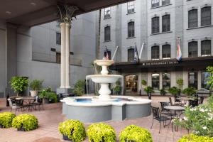 a fountain in front of a building with tables and chairs at The Riverfront Hotel New Orleans in New Orleans +69 photos