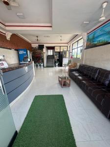 a living room with a black couch and a green rug at Exclusive Premier Park Tvm in Trivandrum