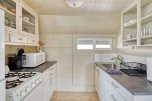 a kitchen with white cabinets and a stove top oven at Stay Portland - Sun-Filled Buckman Studio! in Portland