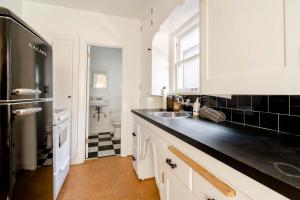 a white kitchen with a sink and a refrigerator at Stay Portland - 1892 Bohemian Dream Studio in Ladd's Addition in Marquam Hill
