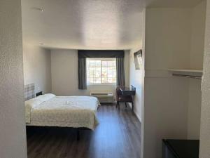 a bedroom with a bed and a window and a desk at Vista Motel in Los Angeles