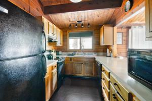 a kitchen with wooden cabinets and a black refrigerator at Mid-century Cabin Hideaway - Hot Tub & Fire Pit in Rhododendron +46 photos