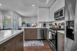 ロサンゼルスにあるPerfect Condo with Pool Spa & Gymの白いキャビネットとステンレス製の電化製品を備えたキッチン