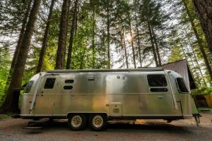 ein silberner Anhänger, der vor einem Wald geparkt ist in der Unterkunft Basecamp Compound - Hot Tubs & Highland Cows in Mount Hood Village