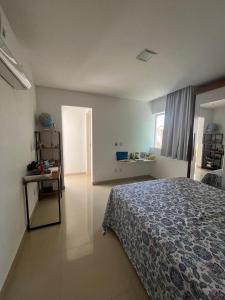 a bedroom with a bed and a table and a window at Casa Miss Paripueira in Paripueira
