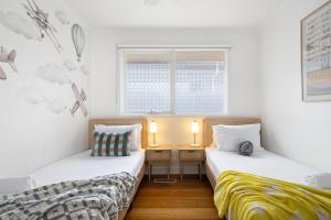 MordiallocにあるRelaxed Bayside Stay with Outdoor Spaceの白い壁の部屋にベッドが2つある