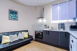 a kitchen with a black couch in a room at 1 BR Flat By Eason Stays Short Lets & Serviced Accommodation Wigan With Free parking! in Wigan