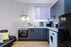 a kitchen with white cabinets and a couch in a room at 1 BR Flat By Eason Stays Short Lets & Serviced Accommodation Wigan With Free parking! in Wigan
