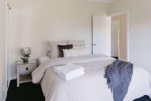 a white bedroom with a large bed and a night stand at Semillon Retreat in Pokolbin